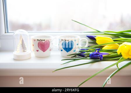Bellissimi fiori-tulipani e iris giacciono sul davanzale con due tazze di caffè. Foto Stock