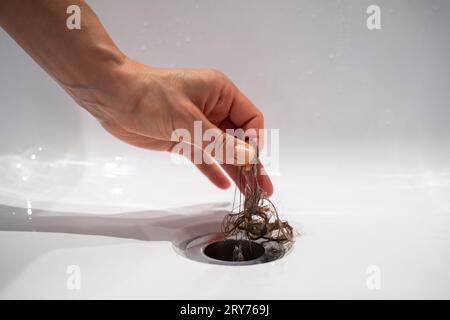 Il foro di drenaggio dell'acqua nella vasca da bagno è ostruito da un grappolo di capelli in bagno a casa. Foto Stock