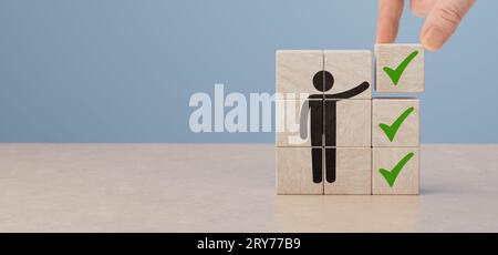 Lista di controllo dei blocchi di legno e icona del segno di spunta verde con la mano sullo sfondo della tabella. Informazioni sulla programmazione degli appuntamenti per la firma dell'attività aziendale. Posto da uomo d'affari Foto Stock