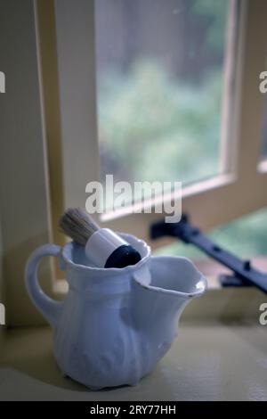 tazza da barba vintage e spazzola da barba su davanzale del vecchio bagno Foto Stock