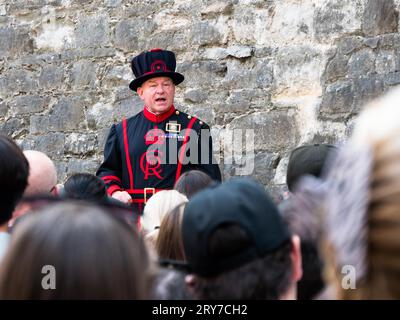 Londra, Inghilterra, 15 giugno 2023: Yeoman nella Torre di Londra in uniforme con lo stemma di re Carlo III rivolgendosi a una folla di turisti: Foto Stock