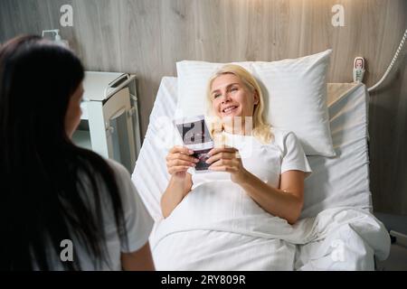 Happy Woman tiene le immagini ecografiche nelle sue mani Foto Stock