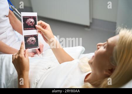 Una paziente felice tiene le immagini ecografiche nelle sue mani Foto Stock