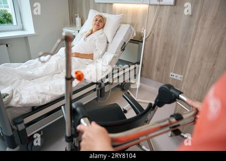 Paziente in un abito da ospedale siede su un letto speciale Foto Stock