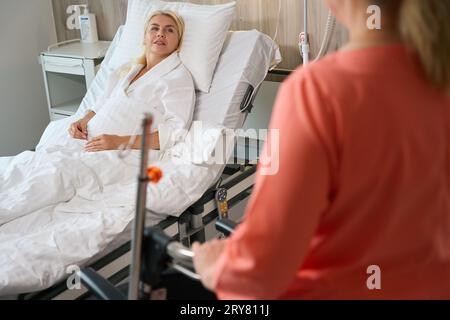 La donna in un abito da ospedale siede su un letto speciale Foto Stock