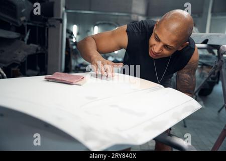 Addetto alla manutenzione della vettura rimuovendo con attenzione le grinze che aderiscono alla carta protettiva Foto Stock