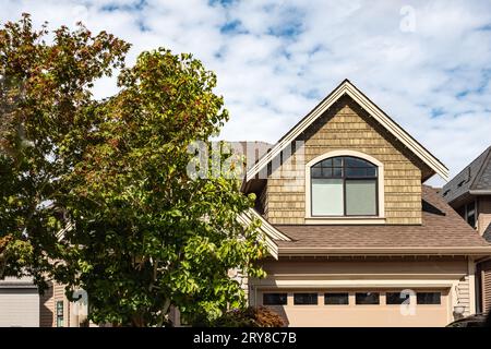 Finestre della casa. Facciata dell'edificio immobiliare in una giornata di sole. Grande casa di lusso su misura con alberi verdi in un giardino. Facciata di un grande cust moderno Foto Stock