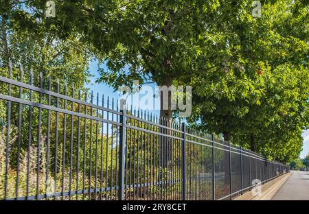 Barriera stradale, proteggere i veicoli da incidenti. Recinzione di ferro lunga e alta lungo la strada. Recinzione su strada. Recinzione in città. Metallo nero Foto Stock