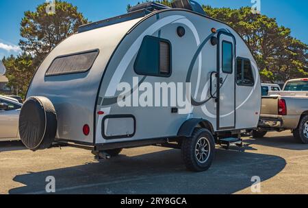 Piccola roulotte tirata dalla macchina. Viaggi in vacanza. Piccola casa su ruote. Stile di vita all'aperto avventuroso. Foto Stock