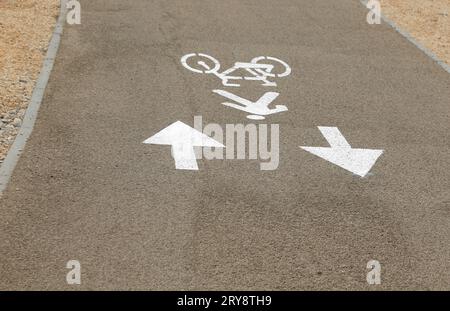 cartelli a terra sulla pista ciclabile con due frecce e area pedonale Foto Stock