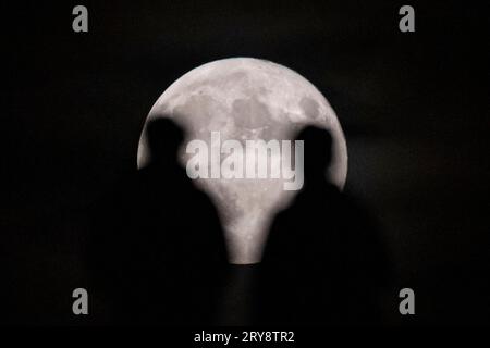 Londra, Regno Unito. 29 settembre 2023. Le persone si sono viste come la Harvest Moon si alza dietro di loro, come visto da Northala Fields vicino Northolt, nella parte ovest di Londra. È così chiamato perché è la luna piena più vicina all'equinozio autunnale. È anche una superluna in quanto è vicino al suo approccio più vicino alla Terra e sembra leggermente più grande e più luminoso del solito. Crediti: Stephen Chung / Alamy Live News Foto Stock