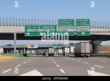 Svincolo autostradale con indicazioni per le principali città italiane e svincoli stradali con camion e automobili Foto Stock