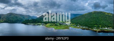 Panorama aereo del lago d'acqua dolce loch Leven con il villaggio di Glen Coe, sopra di esso, il Pap of Glencoe, Highlands, Scozia, alto 742 metri Foto Stock