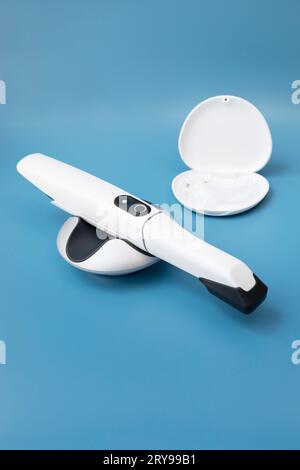 Scanner per denti dentari intraorali 3d bianco e guardia notturna dei denti in scatola su sfondo blu. Apparecchiature odontoiatriche, dispositivo per la scansione dei denti. Odontoiatria e. Foto Stock