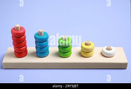 Impilare e contare pezzi di legno su sfondo viola. Giocattolo educativo per lo sviluppo di abilità motorie Foto Stock