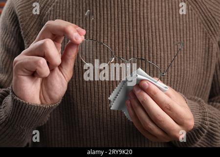 Uomo che pulisce gli occhiali con un panno in microfibra, primo piano Foto Stock