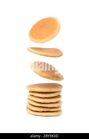 Molti gustosi pancake freschi che cadono su sfondo bianco Foto Stock