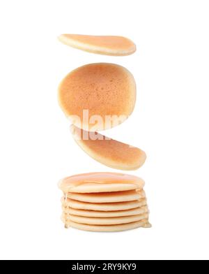 Molti gustosi pancake freschi che cadono su sfondo bianco Foto Stock