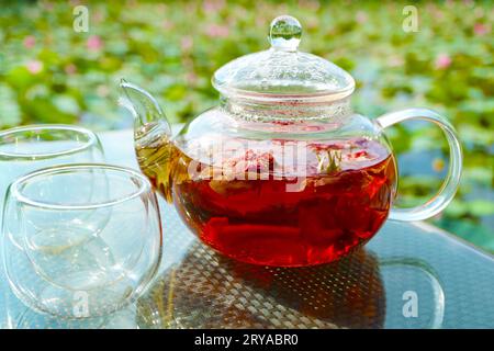 Primo piano del tè alle rose immerso in una teiera sul tavolo del giardino Foto Stock