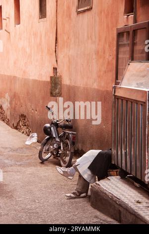 Gambe riposanti e bicicletta parcheggiata nella strada laterale di Marrakech in Marocco, marzo 2012 Foto Stock