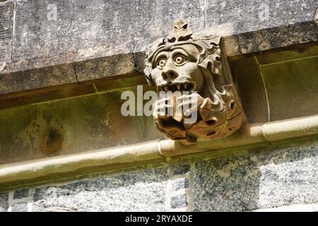 Un divertente gargoyle in pietra tiene la lingua mentre fissa, con gli occhi larghi, dalla sua posizione vicino alla cima del Lews Castle a Stornoway, Lewis Island, Scozia Foto Stock