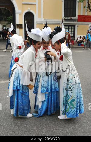 Gli artisti in costume si riuniscono intorno a una macchina fotografica per guardare le foto del loro spettacolo di danza in un festival culturale giapponese nel centro di Hanoi, in Vietnam Foto Stock
