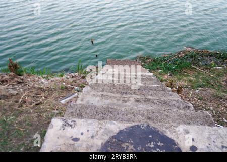 I gradini che conducono al lago sono fatti di cemento con terreno rosso intorno ad esso. visto dall'alto. Foto Stock