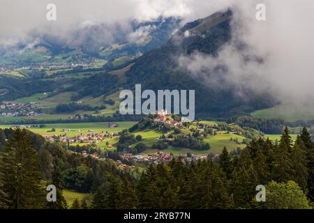 Vista del villaggio medievale di Gruyères nel cantone di Friburgo dall'Alpe di Moléson. Moléson, Svizzera. Vista del villaggio di Gruyère nel cantone di Friburgo. Sullo sfondo, il tipico paesaggio culturale svizzero, un mosaico di boschi e pascoli. La città medievale di Gruyères, con il castello di Gruyères, si trova su una collina ai piedi delle Prealpi nel cantone di Friburgo. La città è senza auto, ha quattro musei ed è stata insignita del titolo di "miglior villaggio turistico" dall'UNWTO nel 2021 Foto Stock