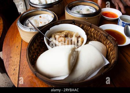 Cosce di maiale stufata con mantou panino cinese al vapore e dim sum o gnocchi nel cestino del locale ristorante caffetteria per i viaggiatori thailandesi Foto Stock