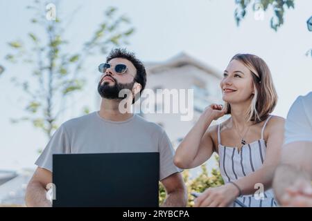 Un team di architetti e designer collabora all'aperto in una moderna area cittadina, discutendo di un progetto su un tablet per un progetto di costruzione. Foto Stock