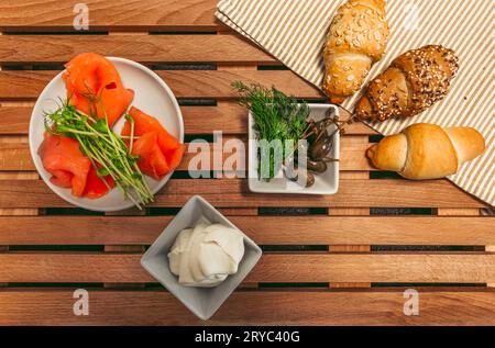 LOX, croissant, panna, capperi e altri ingredienti preparati per cucinare - vista dall'alto. Panino tradizionale con croissant francesi con filetto di salmone Foto Stock