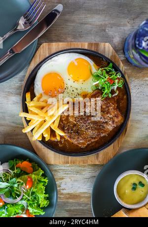 Bistecca di manzo vietnamita con patatine fritte, uova fritte, baguette, servita con bevanda alla limonata, insalata di verdure Foto Stock