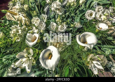 Bouquet di fiori bianchi, rose, gigli di calla e foglie verdi Foto Stock