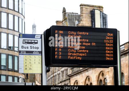 Un segnale di fermata dell'autobus a LED con una versione precedente sullo sfondo, Glasgow, Scozia, Regno Unito, Europa Foto Stock