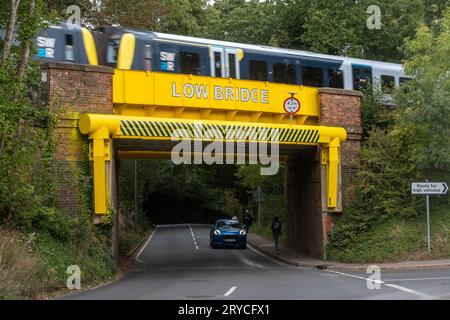 Un ponte ferroviario spesso colpito da veicoli alti camion recentemente verniciati di giallo brillante, Wrecclesham, Surrey, Inghilterra, Regno Unito. Ponte basso Foto Stock