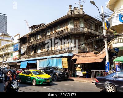 Un'antica struttura residenziale in legno nel mezzo del traffico stradale di Bangkok, Thailandia. Foto Stock