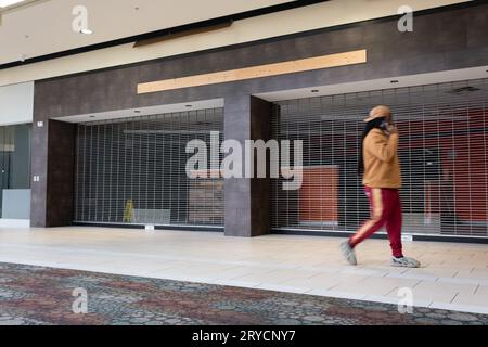 Giovane che cammina accanto a negozi chiusi presso il centro commerciale Genesee Valley Center di Flint Township Michigan Foto Stock