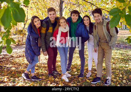 Amici felici con giacche calde e sciarpe posano insieme per una foto. Foto Stock