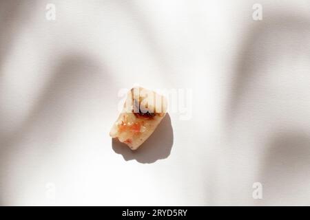 Un dente estratto distrutto con carie e un foro al centro giace su uno sfondo bianco, masticando il dente molare, il dente della saggezza, l'estrazione del dente Foto Stock