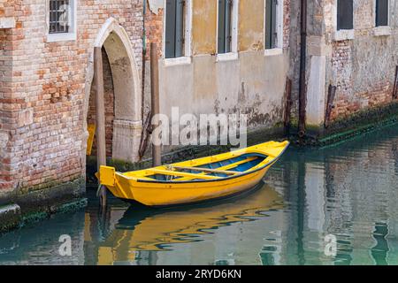 Pittoresca scena idilliaca con una barca gialla ormeggiata o ormeggiata sui canali d'acqua di Venezia, Italia. Foto Stock