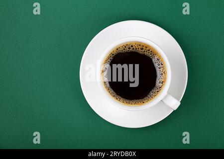 White tazza di caffè nero sul piattino su verde Foto Stock