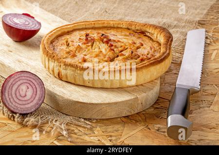 Torta di cipolle francesi con pancetta sul tavolo da cucina, tagliate la cipolla e il coltello sul tavolo da cucina Foto Stock