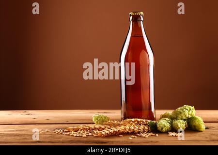 Primo piano: Bottiglia di birra marrone, luppolo, orzo sul tavolo Foto Stock