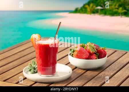 Scenario di vacanza con frullato di fragole e spiaggia tropicale sullo sfondo Foto Stock