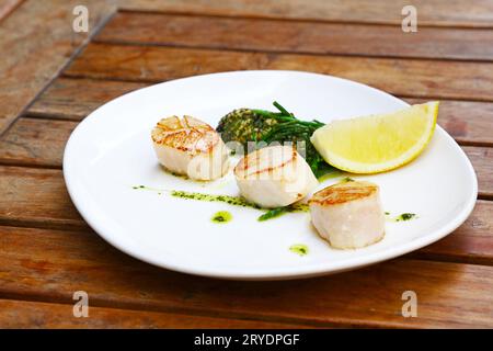 Porzione di capesante grigliate sul piatto sul tavolo Foto Stock