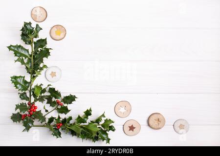 Sfondo natalizio naturale. Tradizionale holly natalizia con bacche rosse su sfondo di legno bianco Foto Stock