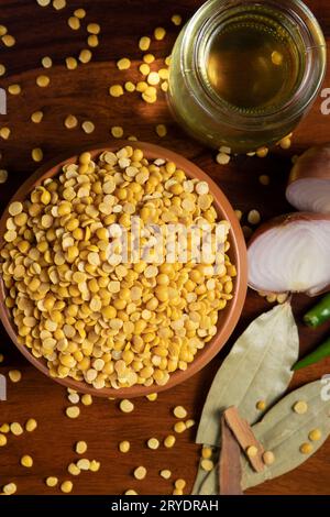 Un recipiente di terra pieno di piselli daal-piccione circondato da olio in contenitore di vetro, cipolla tagliata a fette, peperoncini verdi, alloro secco e cannella Foto Stock