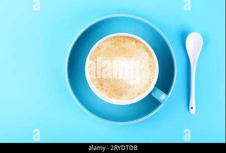 Tazza completa di caffè cappuccino con latte su carta blu Foto Stock