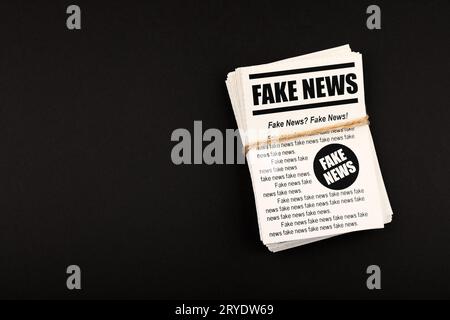 Pila di giornali di NOTIZIE FALSE su nero Foto Stock