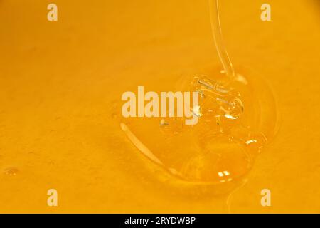 Chiudere versando del miele liquido fresco nel recipiente Foto Stock